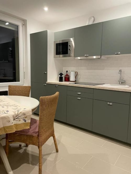 Cuisine moderne à l'Appart Hôtel Panambi avec armoires vert sauge, carrelage blanc et coin repas à Chevilly-Larue