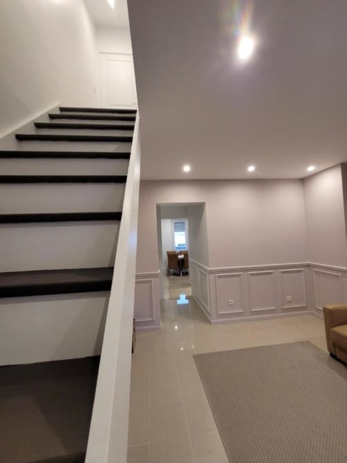 Couloir moderne avec escalier aux contours noirs, lambris blanc, éclairage encastré et sol beige à l'Appart Hôtel Panambi
