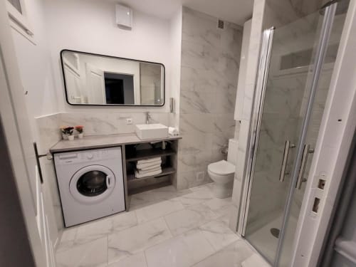 Salle de bain moderne à l'Appart Hôtel Panambi avec carrelage marbre, machine à laver intégrée, vasque et douche à l'italienne