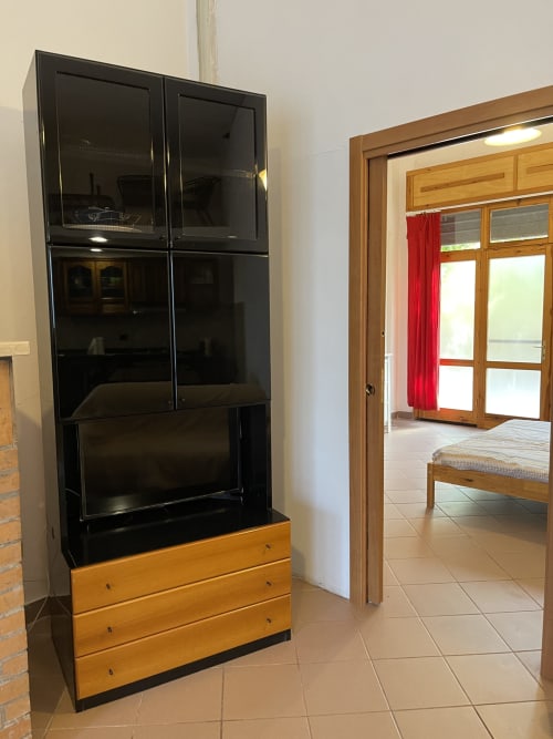 Credenza nera e in legno con ante in vetro nell'appartamento Rigiariloo, San Giacomo degli Schiavoni, con vista verso la camera da letto