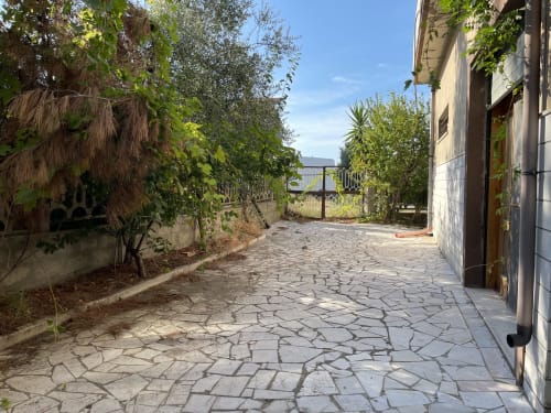 Viale del giardino presso Rigiariloo Home Apartments a San Giacomo degli Schiavoni con patio in pietra, vegetazione rigogliosa e edificio