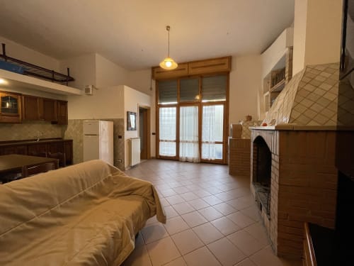 Ampio soggiorno dell'appartamento Rigiariloo Home Apartments con camino, cucina e vista sul giardino a San Giacomo