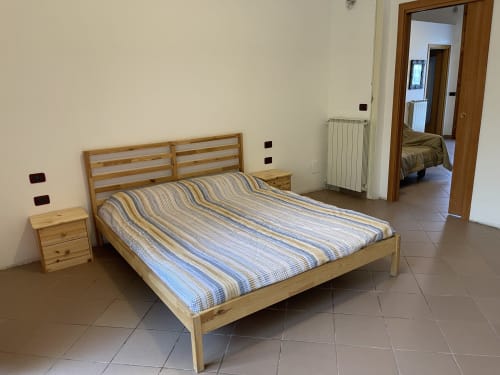Letto in legno con biancheria a righe nella luminosa camera degli Appartamenti Rigiariloo Home, San Giacomo degli Schiavoni