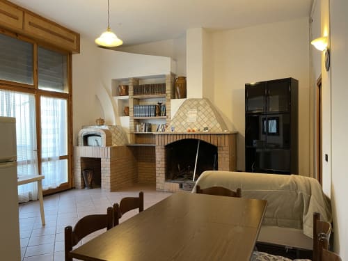 Ampio soggiorno-cucina con camino, mobili in legno e vista sul giardino presso Rigiariloo Home Apartments