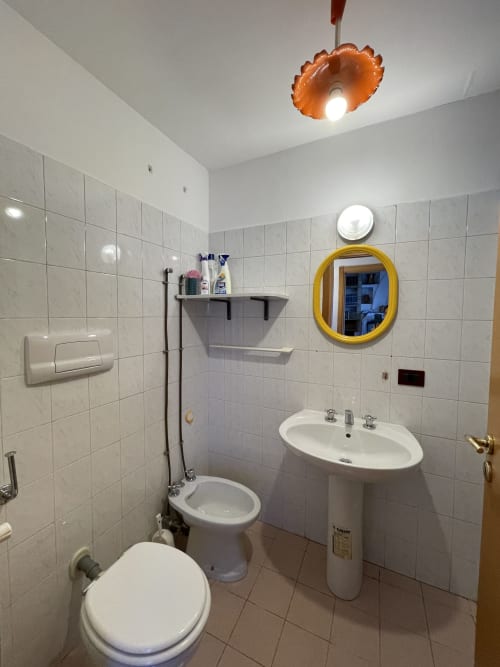 Bagno moderno presso Rigiariloo Home Apartments con lavabo a colonna, toilette, doccia e specchio dorato