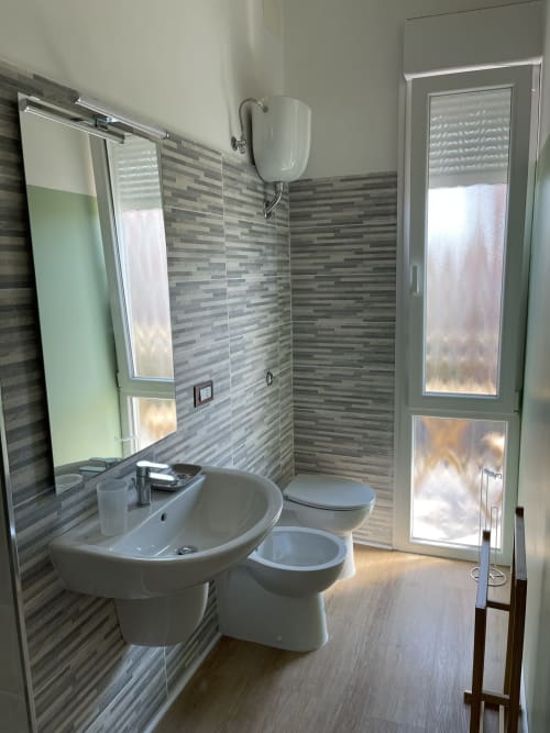 Moderno bagno presso Rigiariloo Home Apartments con doccia walk-in, lavabo, wc e vista città a San Giacomo degli