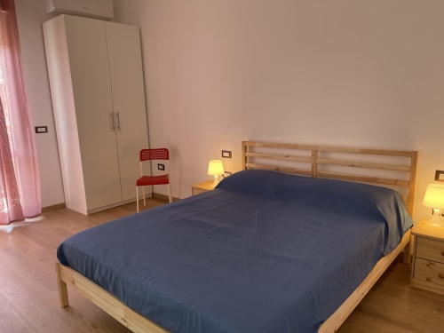 Camera luminosa agli Appartamenti Rigiariloo a San Giacomo degli Schiavoni con letto in legno, biancheria blu, armadio e atmosfera calda