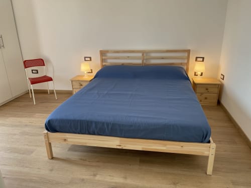 Camera da letto moderna con biancheria blu, letto in legno e comodini con lampade presso Rigiariloo Home Apartments, San Giacomo degli
