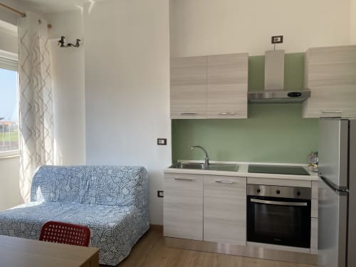 Cucina moderna con rivestimento verde e zona living presso Rigiariloo Home Apartments, San Giacomo degli Schiavoni