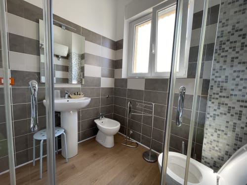 Bagno moderno negli Appartamenti Rigiariloo, San Giacomo degli Schiavoni, con piastrelle a righe, doccia, lavandino, bidet e