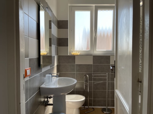 Bagno moderno negli Appartamenti Rigiariloo con lavandino, wc e vista sulla città dalle finestre