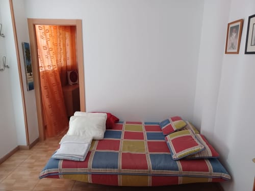 Bedroom at Casa Ferrer Barcelona apartment in L'Hospitalet de Llobregat with colorful bedding, white pillow, and orange