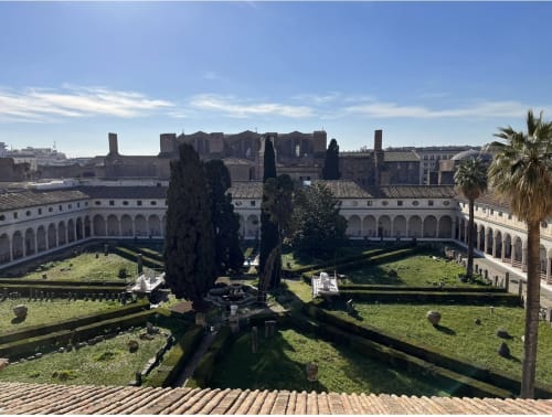 Cortile romano con cipressi, antiche rovine e colonnato ad archi presso Michelangelo Suite Roma