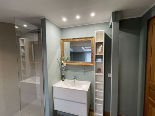 Salle de bain moderne avec vanité blanche, miroir doré, mur accent vert et douche vitrée aux Gîtes Boulogne Sur