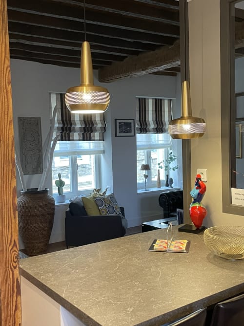 Salle à manger moderne avec luminaires suspendus dorés et plan de travail en pierre aux Gîtes de Boulogne-sur-Mer
