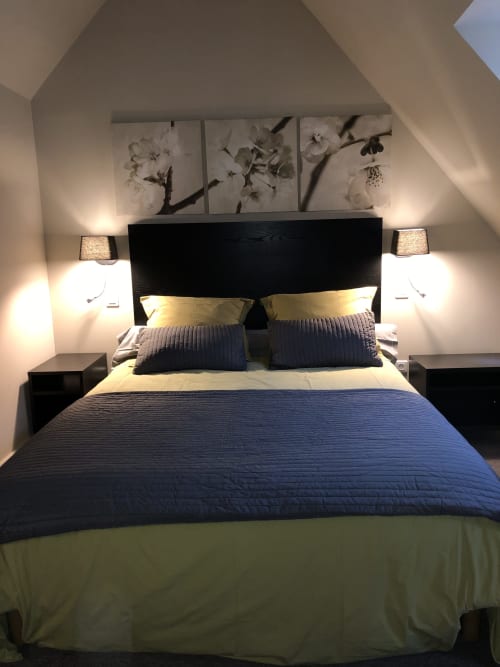 Chambre moderne aux Gîtes Boulogne Sur Mer avec lit noir, parure bleue, décoration florale murale et lampes de chevet