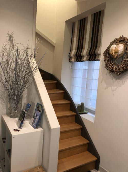 Escalier du gîte Boulogne Sur Mer avec marches en bois, murs blancs, branches décoratives et couronne tressée