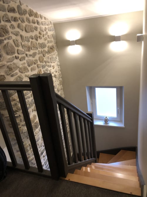 Escalier contemporain avec mur en pierre, rampe noire et éclairage moderne dans un cottage de Boulogne-sur-Mer