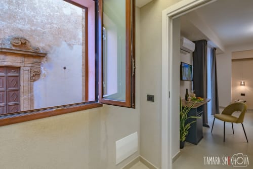 Camera d'hotel moderna a Sciacca con vista città dalla finestra in legno, scrivania con comfort e accesso alla zona notte