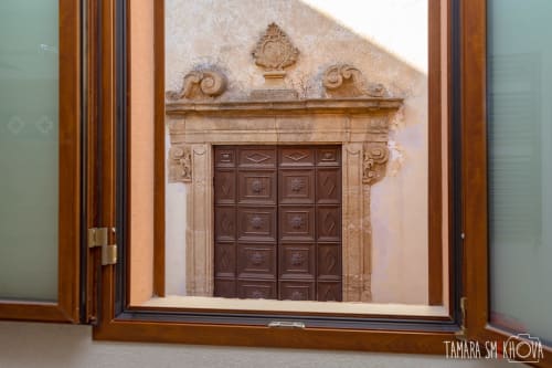 Vista attraverso porte aperte di una porta in legno ornato con arco in pietra scolpita a Macramè Fazello a Sciacca, Sicilia