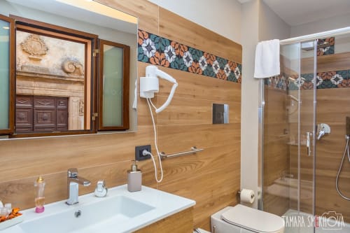 Bagno moderno della Stanza Perricone di Macramè Fazello a Sciacca: pareti in legno, doccia in vetro, lavabo e specchio con vista città