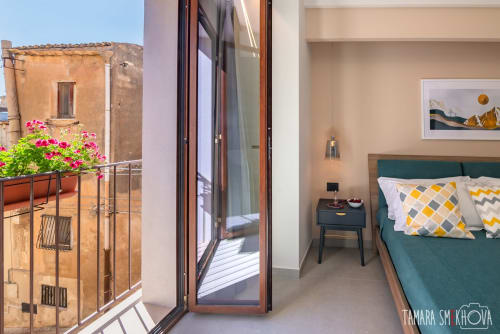 Camera Nerello a Macramè Fazello, Sciacca: camera con letto verde e balcone con vista su edificio storico in pietra