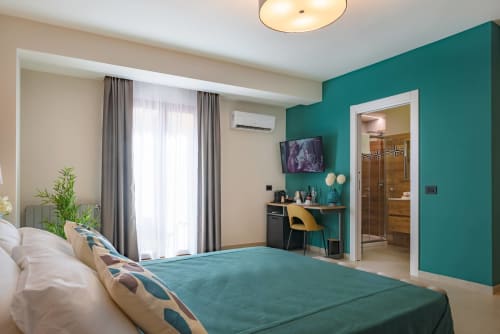 Camera moderna al Macramè Fazello di Sciacca con parete azzurra, letto matrimoniale, scrivania e bagno privato