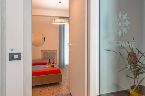 Ingresso della Insolia Room al Macramè Fazello B&B di Sciacca: camera da letto con biancheria rossa e comfort moderni