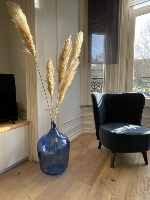 Salon contemporain aux Gîtes Boulogne Sur Mer avec fauteuil wingback noir, vase bleu garni de pampa et vue sur le monument