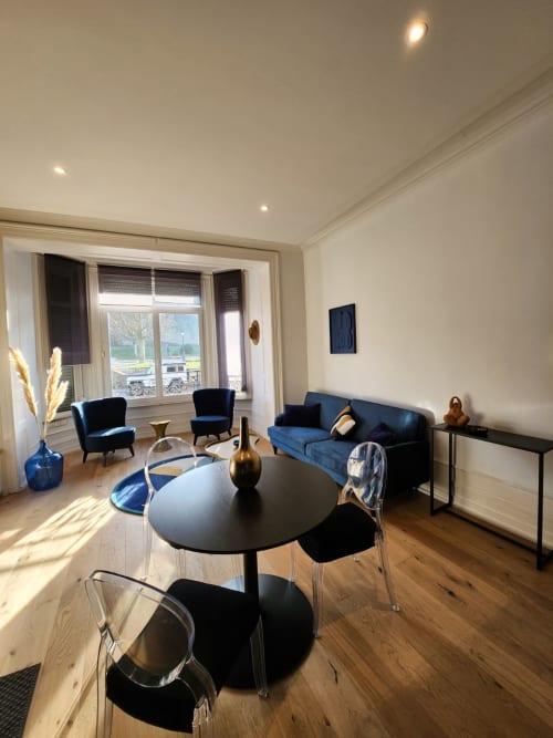 Séjour moderne avec canapé bleu et table ronde noire aux Gîtes Boulogne Sur Mer, grandes fenêtres avec vue sur le monument