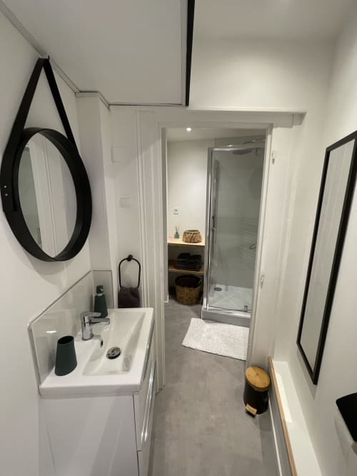 Salle de bains moderne du cottage de Boulogne-sur-Mer avec lavabo blanc, miroir rond, douche et carrelage gris