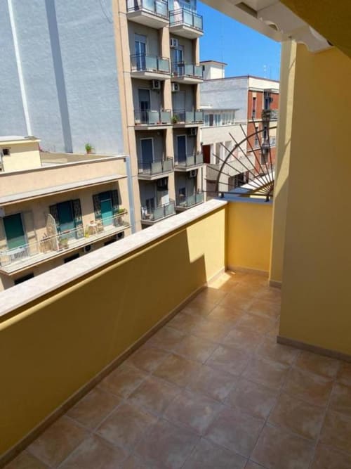 Balcone giallo affacciato sulla corte interna dell'hotel La Maison a Bari circondato da edifici