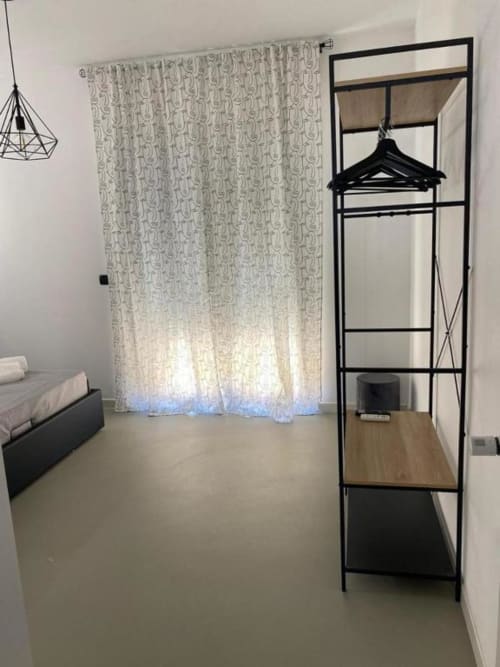 Camera da letto moderna a La Maison a Bari con scaffalatura in metallo nero, tende decorate e lampada sospesa contemporanea