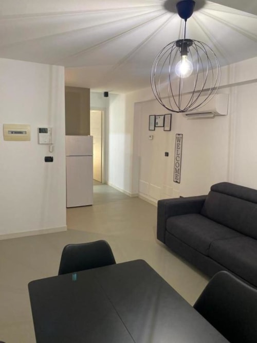 Interno moderno dell'appartamento a La Maison a Bari con tavolo da pranzo nero, divano, lampada sospensione sferica e zona cucina