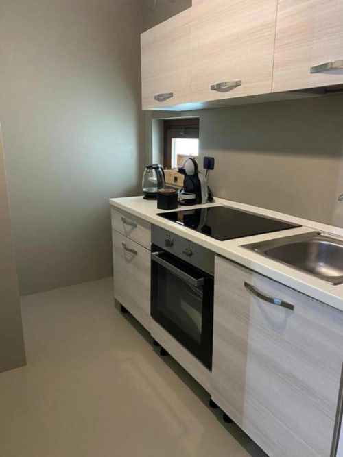 Cucina a corridoio moderna nell'appartamento La Maison a Bari con mobili bianchi, piano cottura a induzione e lavello in acciaio inossidabile
