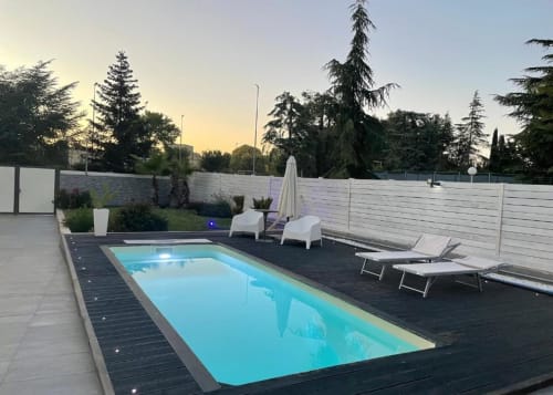 Villa moderna con piscina riscaldata, lettini e ombrellone nel giardino di Bari al tramonto