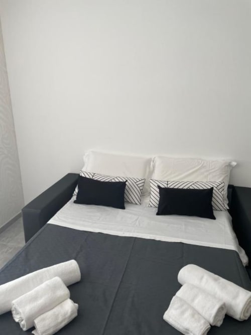 Camera da letto della villa moderna a La Maison Srls, Bari con biancheria bianca e nera, cuscini e asciugamani arrotolati