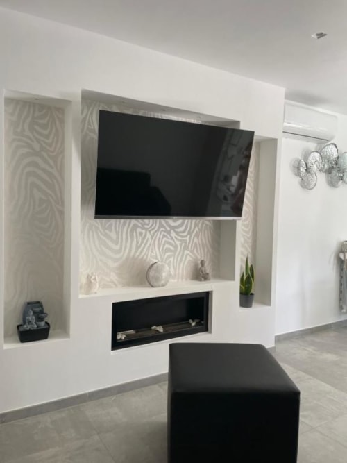 Moderno soggiorno con TV a parete, camino e carta da parati a righe zebrate nella villa La Maison, Bari