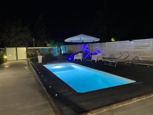 Vista notturna di Villa La Maison a Bari con piscina illuminata, area lounge, ombrellone e giardino