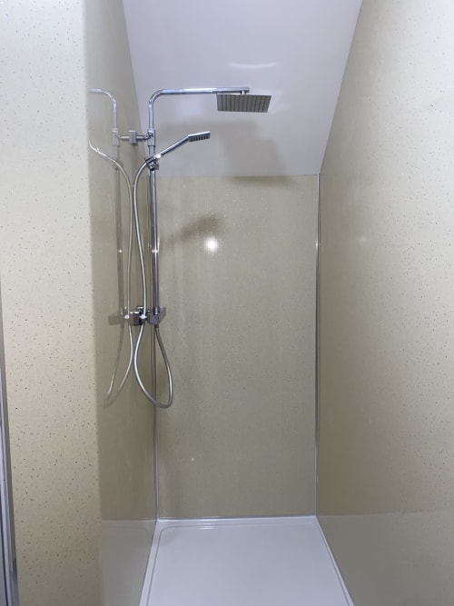 Modern shower enclosure with chrome fixtures and rainfall showerhead at Duffy Lodge apartment in Co Donegal