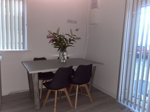 Modern dining area at Duffy Lodge with table, black chairs, and pink lilies in vase near bright windows overlooking Co