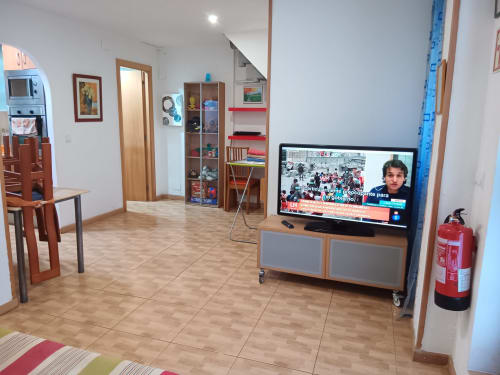 Open-plan apartment living room at Casa Ferrer Barcelona with TV, wooden furniture, kitchen area, and fire extinguisher