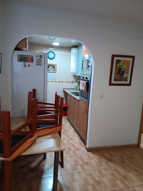 Kitchen dining area at Casa Ferrer Barcelona apartment with wooden chairs, equipped kitchen, and white appliances in