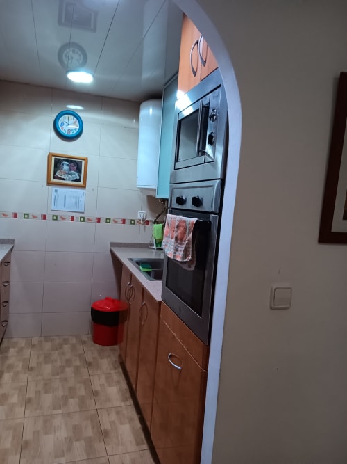 Modern kitchen in Casa Ferrer Barcelona apartment with stainless steel oven, wooden cabinets, and white tile walls