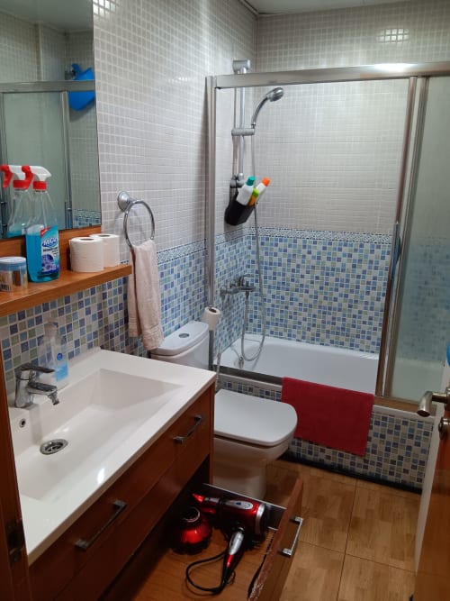 Modern bathroom with blue mosaic tiles, wooden vanity, glass shower enclosure at Casa Ferrer Barcelona apartment