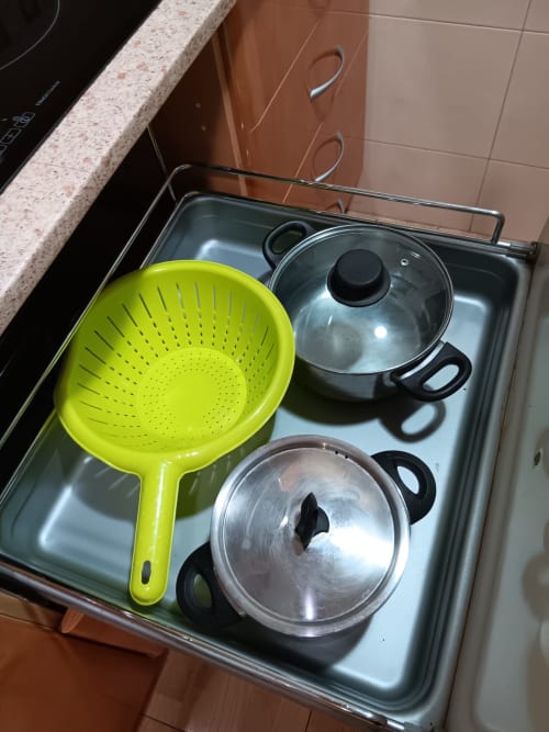 Kitchen cookware in apartment drawer: yellow colander, stainless steel pots with lids at Casa Ferrer Barcelona