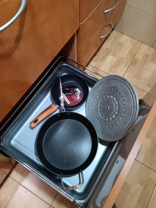 Kitchen cookware drawer in Casa Ferrer Barcelona apartment showing pans, pots, colander, and utensils.