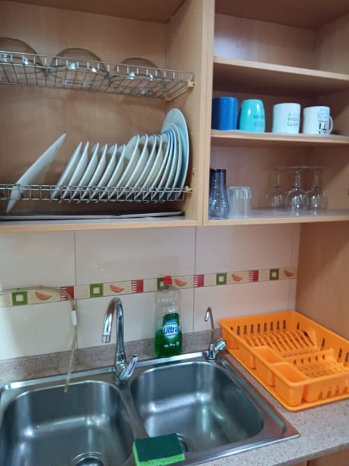 Kitchen sink area with dish rack, shelves with plates and glassware at Casa Ferrer Barcelona apartment