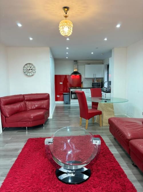 Modern open-plan living area in Sunbeam Haven bungalow with red leather furniture, glass coffee table, kitchen with red