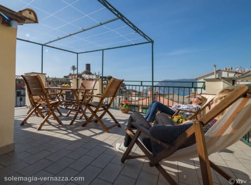 Donna che si rilassa sulla sdraio della terrazza SoleMagia con vista sul mare a Vernazzo, Italia